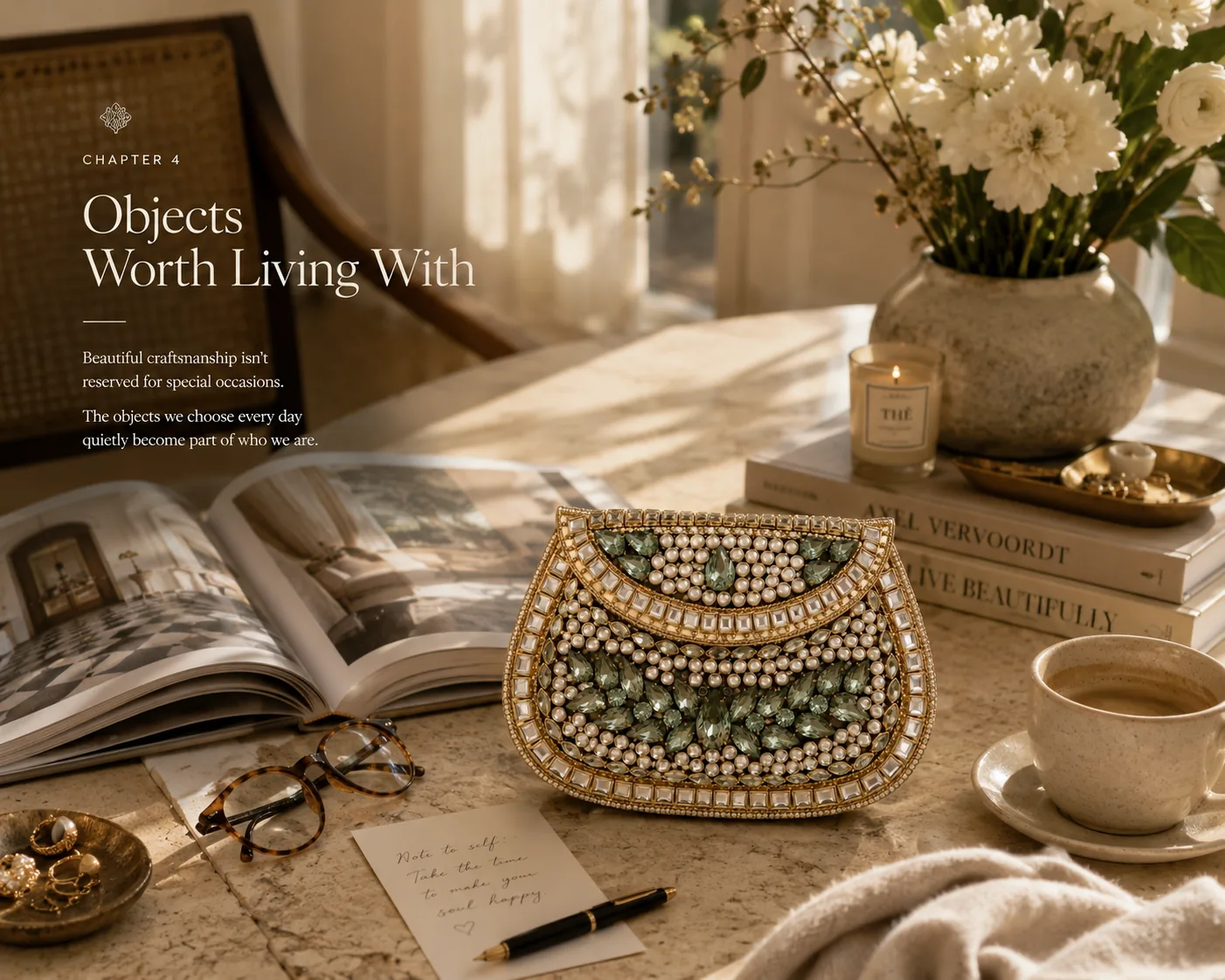 A Kundan clutch with green decorative stones on a warm sunlit table with books, flowers and coffee